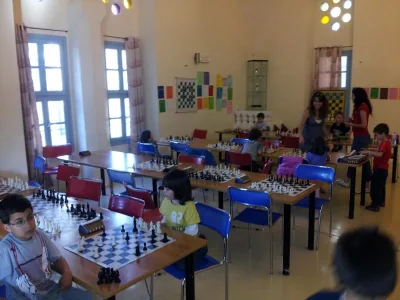 Γενική άποψη της αίθουσας με τραπέζια, σκακιέρες και παιδιά.
