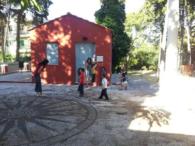 Παιδιά παίζουν με μπάλα στην αυλή, μπροστά από το κόκκινο κτίριο.